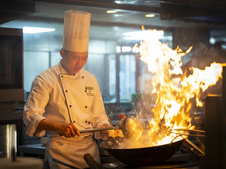 面對騰起的火舌，黃志偉主廚盡顯控火技巧。他在高溫中翻炒「新加坡辣椒蟹」，利用瞬間溫差激發迷人「鑊氣」。台北遠東香格里拉提供