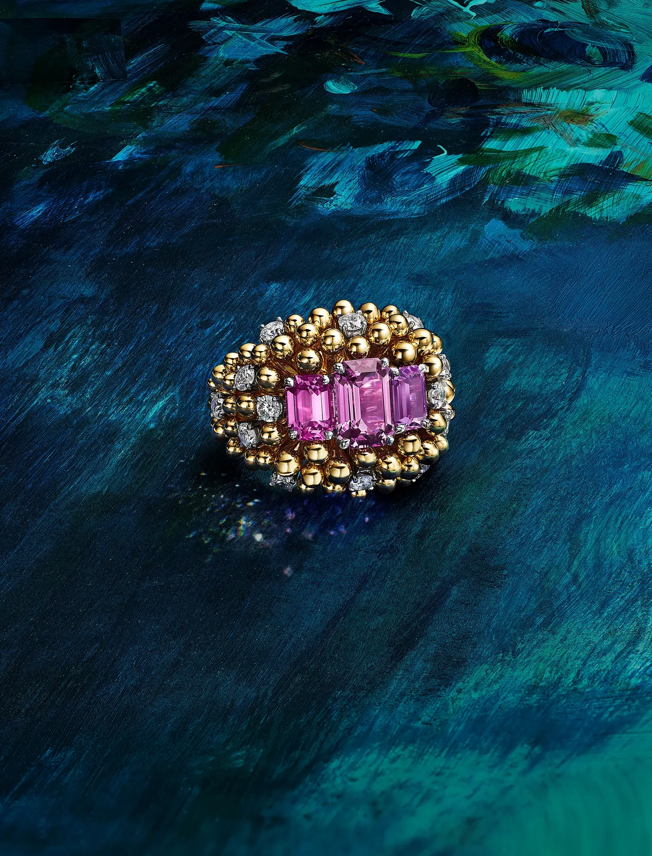 金蕊綻芳篇章鉑金和黃K金戒指，鑲嵌兩顆總重4.47克拉的未經處理的祖母綠切割粉紅色藍寶石、一顆1.55克拉的未經處理的祖母綠切割紫色藍寶石和鑽石。品牌提供