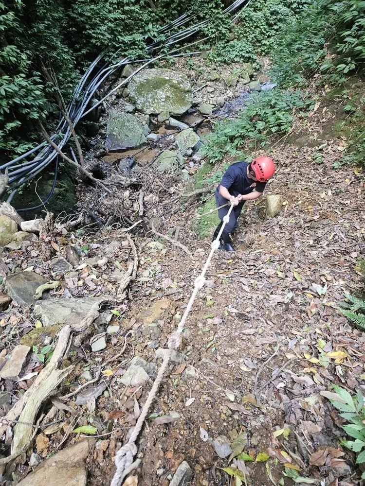 消防局用繩索將失足患者拉上步道。翻攝畫面