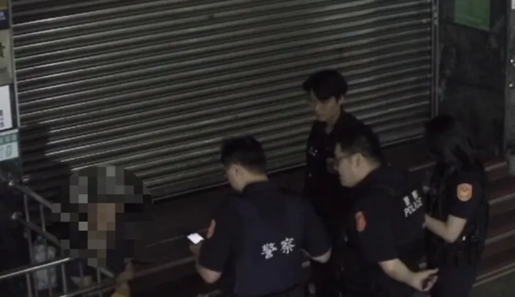 楊男坐在郵局台階前，遭警方盤查。翻攝畫面