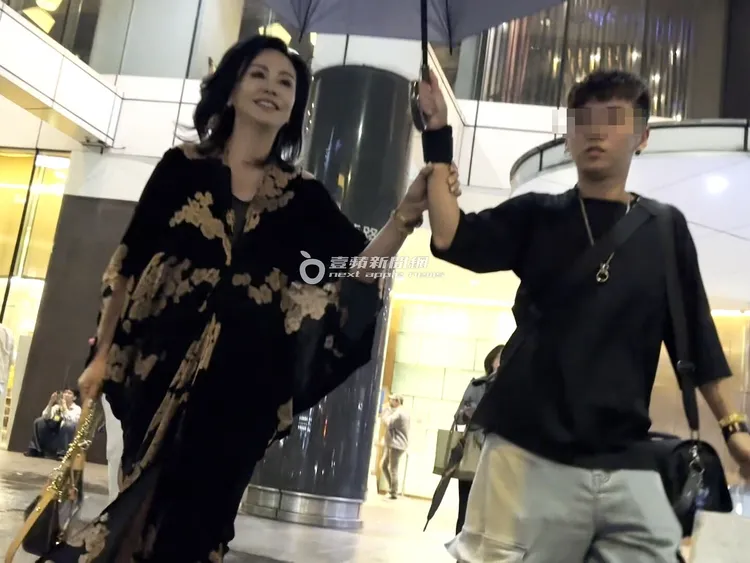 夜晚飄起細雨，助理幫田麗撐傘離開錢櫃。特勤中心攝