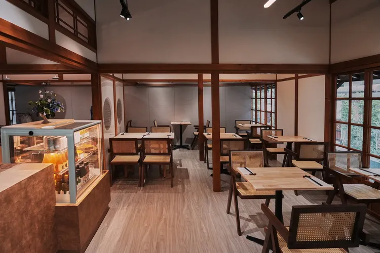 「豆舞YUDOFU」室內空間延續老建築的結構語彙，裸露的木構樑柱在挑高空間中交織成鮮明的節奏，展現時間雕琢出的紋理與力量。業者提供
