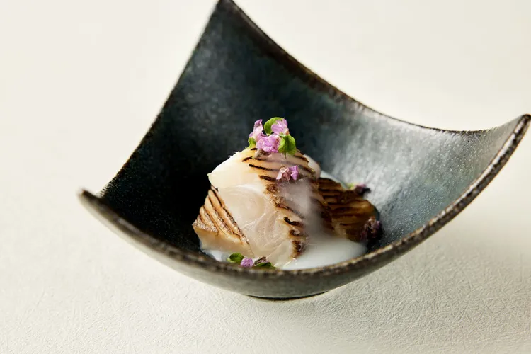 令人回味無窮的「炙烤太刀魚白米醬汁」表皮經炙烤處理，內裡魚肉清甜，淋上以頂級輝映米與吟釀清酒慢熬而成的醬汁，襯托出和食溫潤的風味。The Ukai Taipei提供