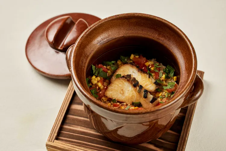 簡單卻充滿季節感的「白魽釜飯」將初夏新鮮番茄與黃櫛瓜以奶油輕炒化為香氣底蘊，魚肉細緻的油脂與鮮味慢慢滲入每一粒米飯之中，令人一口接著一口回味不已。The Ukai Taipei提供
