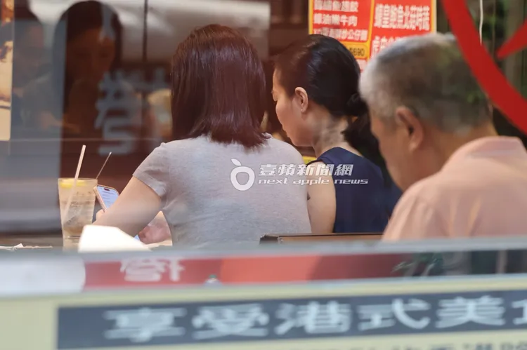 王俐人（左）等待餐點時，坐到經紀人身邊打開手機討論工作。特勤中心攝