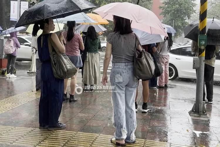 王俐人（右）跟經紀人等綠燈，被雨水噴成濕背秀。特勤中心攝