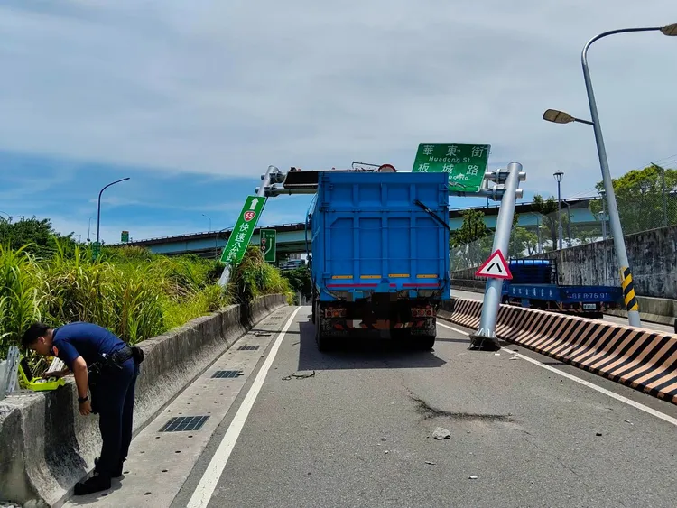 大貨車撞倒限高桿遭卡住動彈不得，吊車到場解圍，道路一度禁止通行。翻攝畫面
