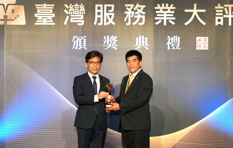 永慶房屋總經理吳良治(右)從金管會主委彭金隆(左)手中接過2026服務金獎獎座。永慶房產集團提供