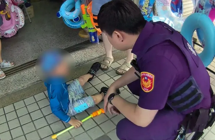 警方手牽穿泳衣的小男童找媽媽。翻攝畫面