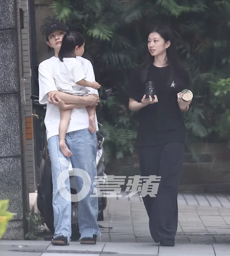 顧穎（右）雙手拿著飲品，李千娜抱著愛子，緩緩返回社區。特勤中心攝