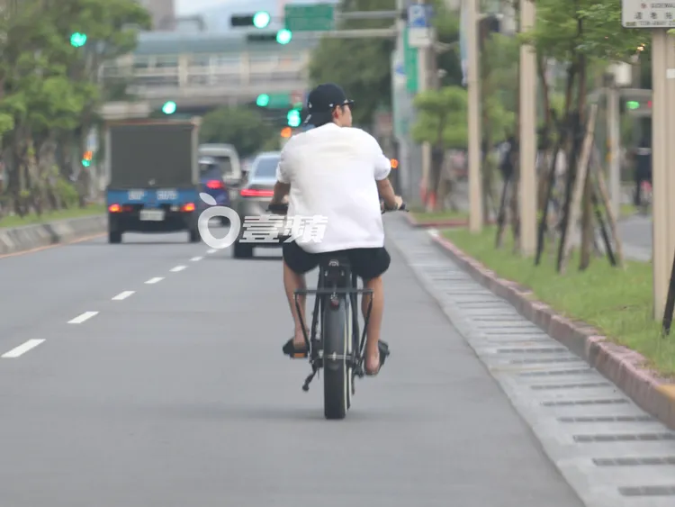 王柏傑一邊騎著電輔車一邊轉頭看著沿路風景，十分愜意。特勤中心攝