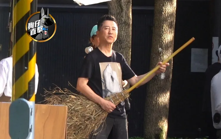 庾澄慶在大直封街拍影片，拿著掃帚作勢彈奏，相當投入。特勤中心攝