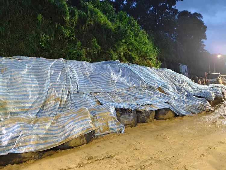 高雄小港松富街擋土牆28日下午倒塌，先以帆布覆蓋崩塌區域。翻攝畫面