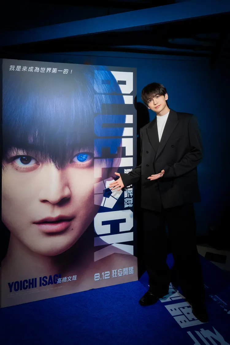 高橋文哉與京站威秀影城「藍色監獄入監通道」的「潔世一」角色海報立牌合影。甲上娛樂提供
