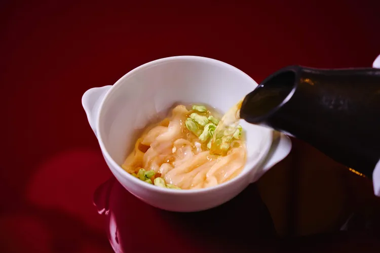 「衝浪象拔蚌吊湯」將象拔蚌切成薄片，現場淋入慢燉三小時的清鮮高湯，瞬間釋放極致鮮甜。業者提供