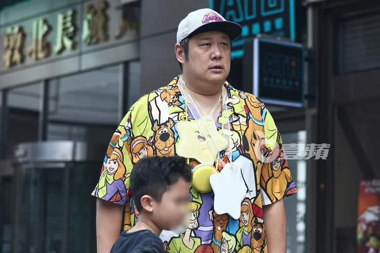 哈孝遠帶著兒子，站在路邊等車。特勤中心攝