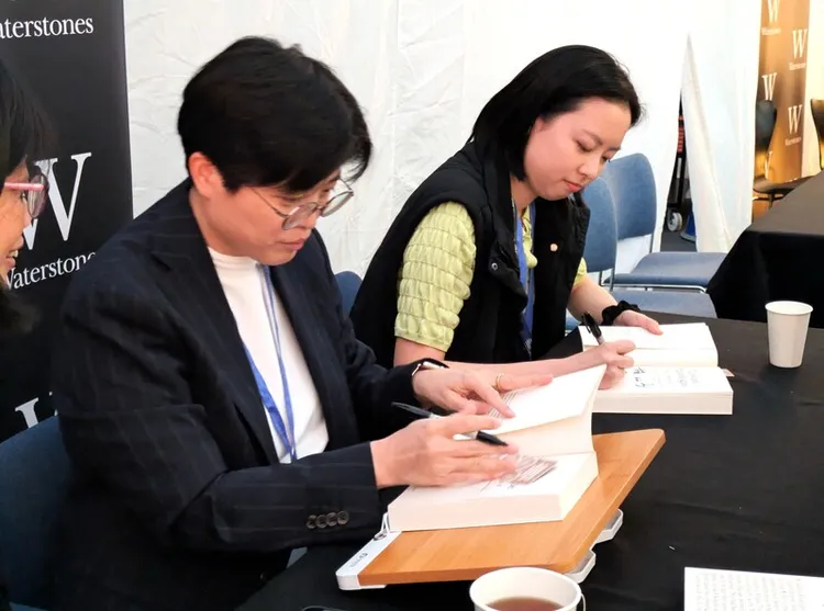 作家楊双子（左）和譯者金翎（右）20日晚間在愛丁堡國際圖書節為讀者簽書。 中央社