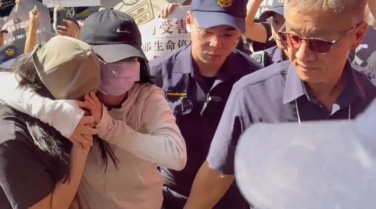 陳尚潔被旁同出庭的親屬壓頭保護走進法院。張欽攝