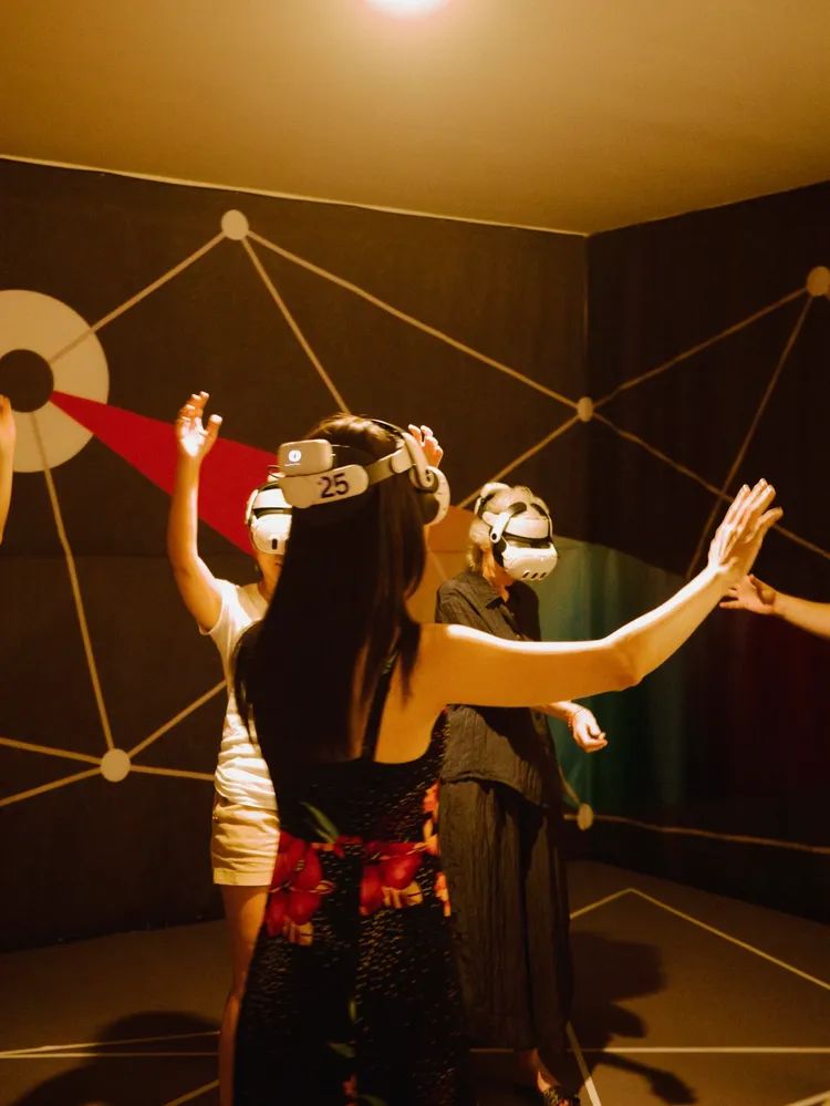 謝盈萱戴上VR裝置後，與同在展示空間的陌生人們產生連結與互動。