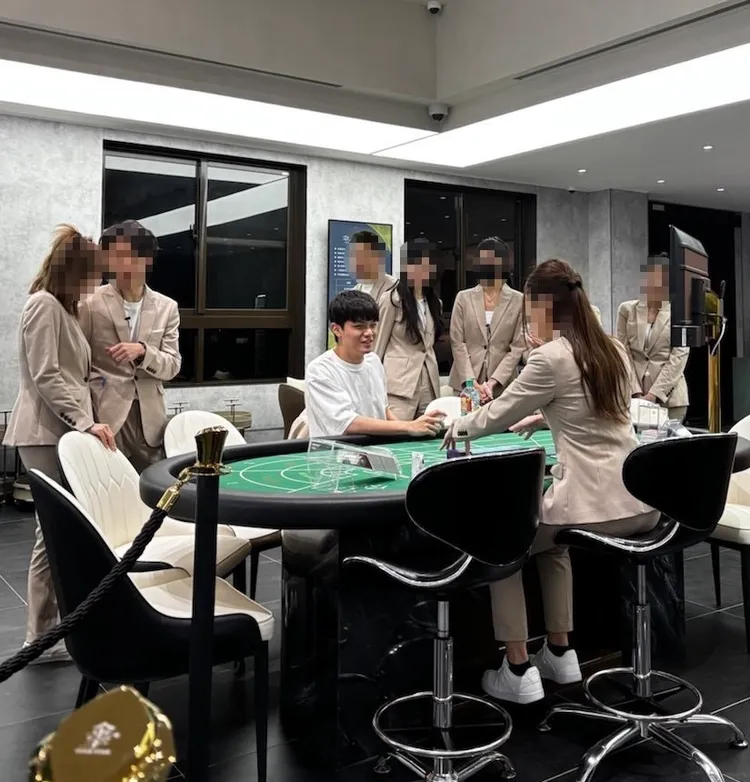 魯佳寶坐在名下桌遊店牌桌上，旁邊圍了一群員工，該店後來被警方查獲是職業賭場，員工是荷官。謮者提供