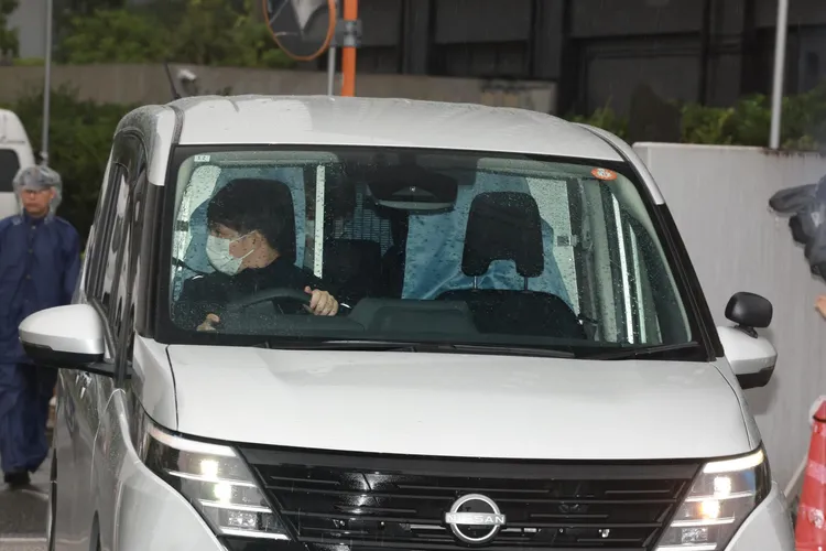 猪俣周杜坐在移送車輛後座，戴著口罩沉思。翻攝dailysports