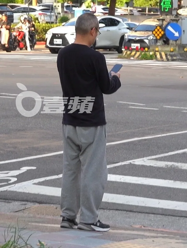 黃立成把握等過馬路時間，拿起手機訊息不漏接。特勤中心攝