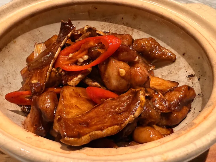 啫啫蕈酥燒雞煲以砂鍋熱騰上桌，雞肉煸炒至焦香，再搭配厚切杏鮑菇吸附醬汁，揭蓋時香氣隨熱氣散出。陳揚盛攝