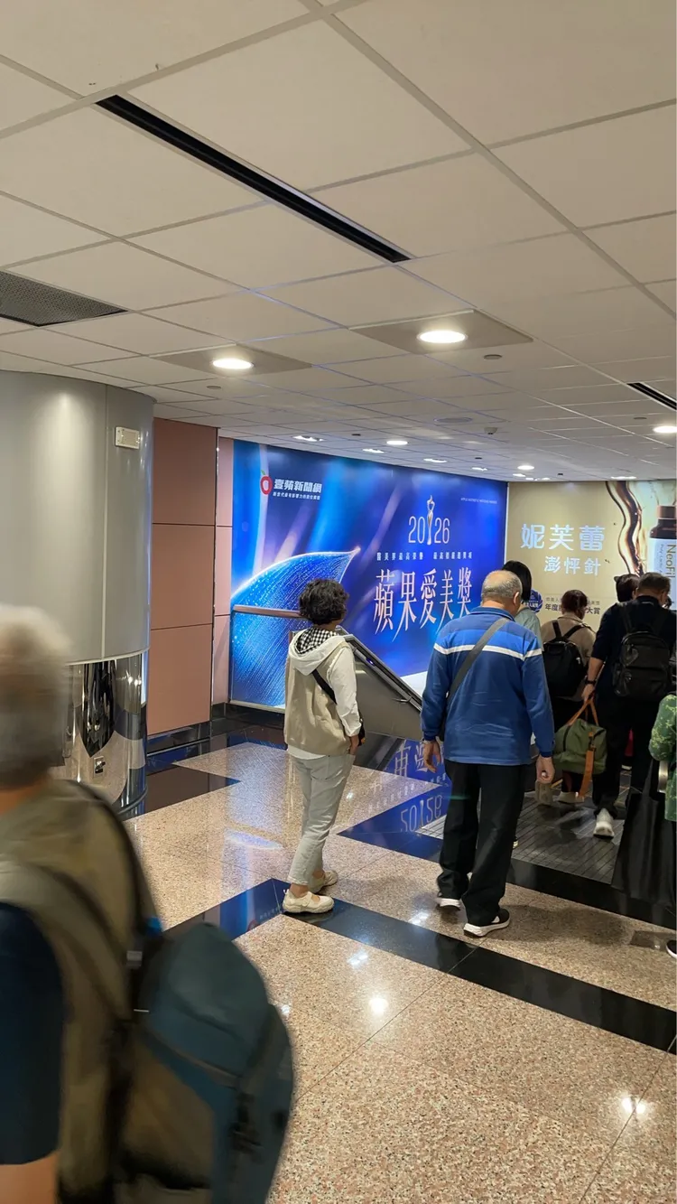 入境旅客行經蘋果愛美獎廣告，準備搭電梯提領行李。讀者提供