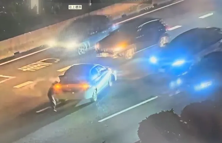 女駕駛立於車後拿三角架。翻攝畫面