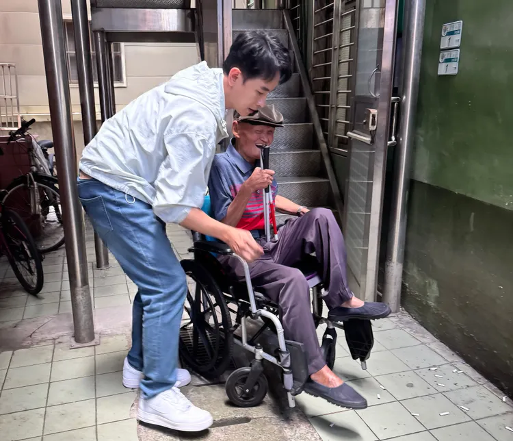 李炳輝行動不便需要協助才能前往淡水河邊演唱。葡萄長文創工作室提供