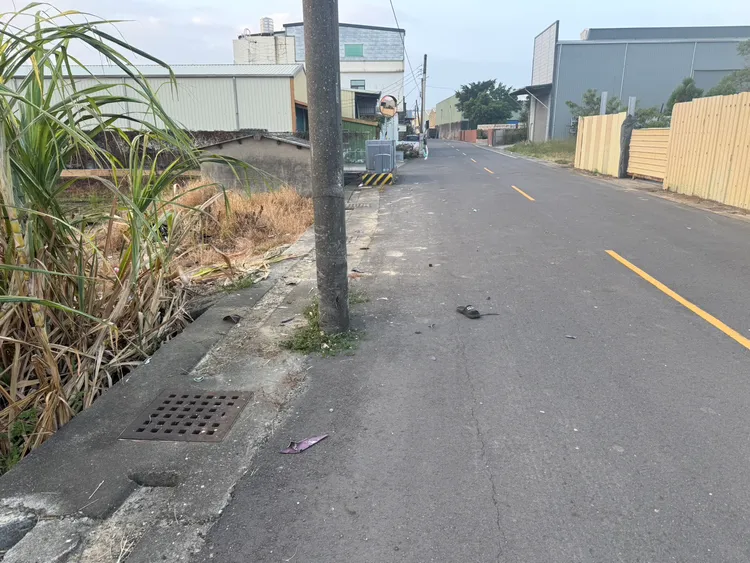 湯男騎機車逆撞電線桿，摔落田裡身亡，馬路上留有拖鞋及機車碎片。民眾提供